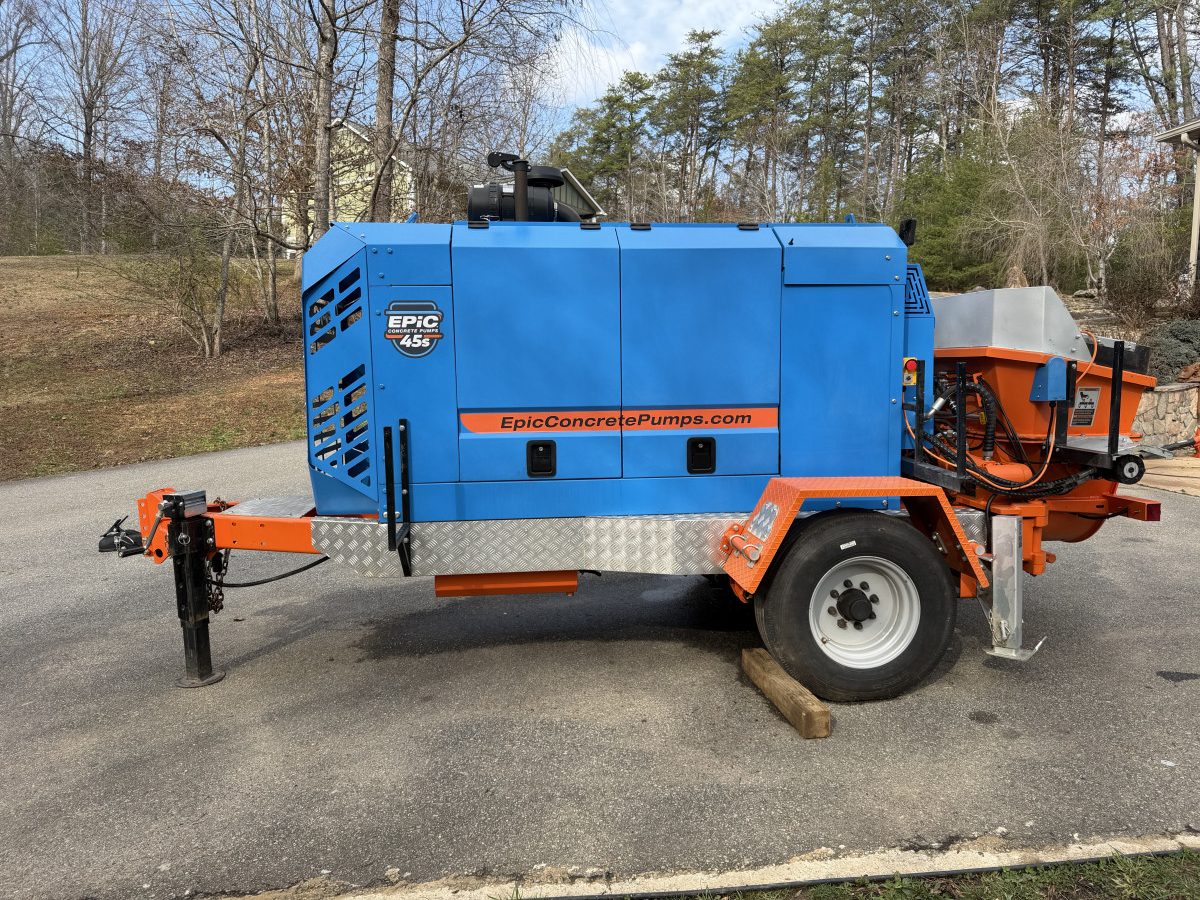 IMG_0222 – Thomas Concrete Machinery Blue towable industrial machine with orange frame and spare wheel on a paved road.