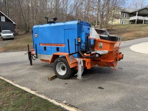 Orange and blue Epic pump parked on a residential street, with a spare tire nearby.