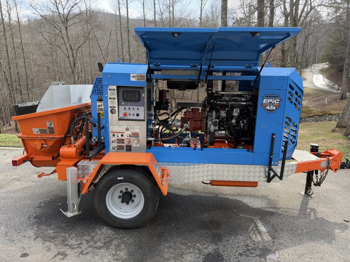 IMG_0227 – Thomas Concrete Machinery Blue Epic 45S pump with orange chute assemblies and exposed engine, parked on a driveway.
